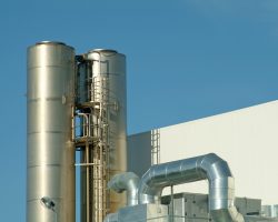 Chimney and pipes of ventilation in plant against sky